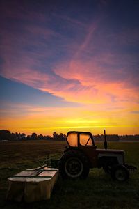 Tractor on field against sky during sunset