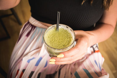 Midsection of woman holding matcha tea