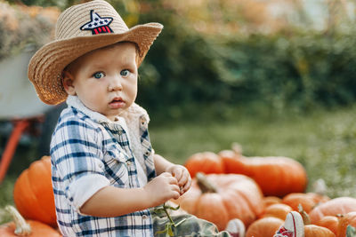 Portrait of a charming baby sitting on pumpkins in the garden or vegetable garden during the harvest 