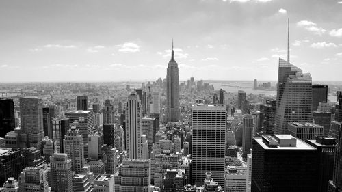 Aerial view of buildings in city against cloudy sky