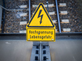 Close-up of yellow high voltage sign on metal