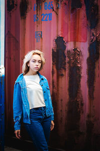 Portrait of woman standing against cargo container