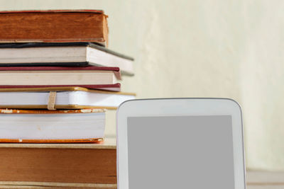 Close-up of digital tablet with books stacked in background
