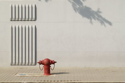 Fire hydrant on sidewalk against wall
