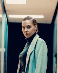 Portrait of beautiful young woman standing against wall