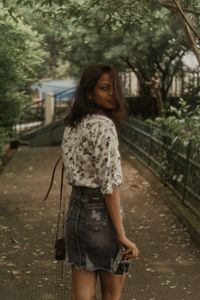 Rear view portrait of woman standing at park