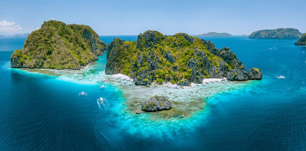 Panoramic view of sea and rocks against blue sky