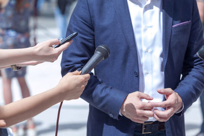 Cropped image of journalist holding microphone and mobile phone