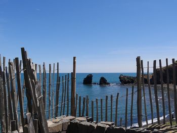 Wooden posts on beach against clear blue sky