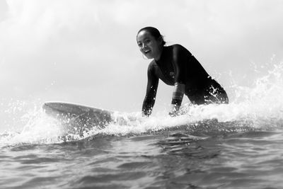 Side view of womamln sitting on a surfboard