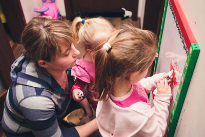 High angle view of mother with children writing on whiteboard at home