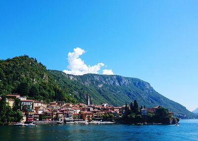 Scenic view of sea by buildings against blue sky