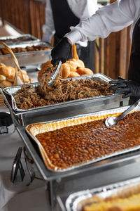 Midsection of people serving food in kitchen