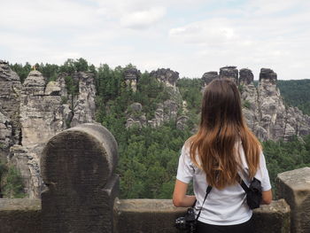 Rear view of woman looking at old ruins against sky