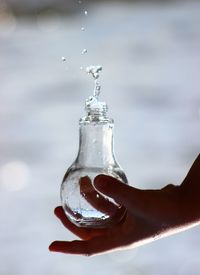 Close-up of hand holding glass bottle against blurred background