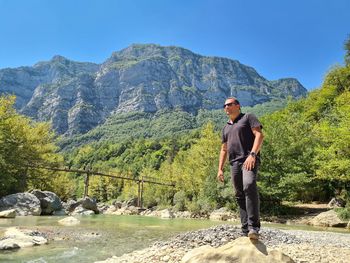 Full length of man standing on rocks against mountains
