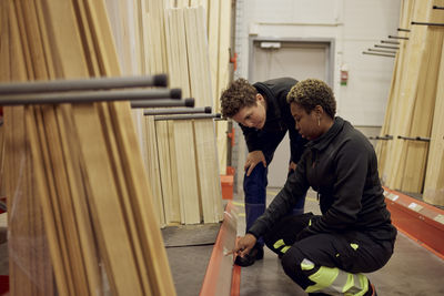 Multiracial female colleagues discussing over label in distribution warehouse of lumber industry