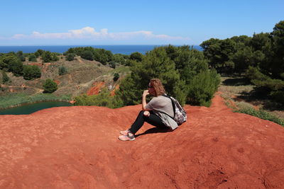 Rear view of man sitting on land against sky