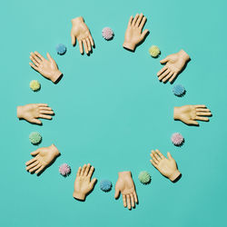 Directly above shot of artificial hands on turquoise background