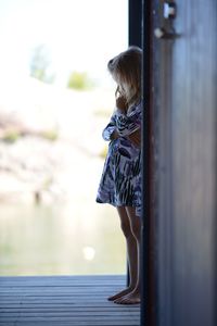 Side view of girl standing at home