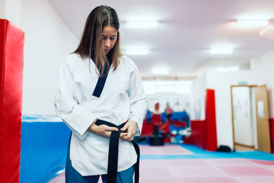 Young woman wearing belt during taekwondo practice