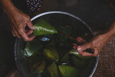 Cropped image of man holding food wrapped in banana leaf