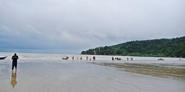 People at beach against sky