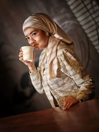 Portrait of young woman sitting on table