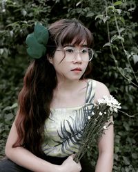 Portrait of young woman standing amidst plants