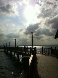 Pier on sea against cloudy sky