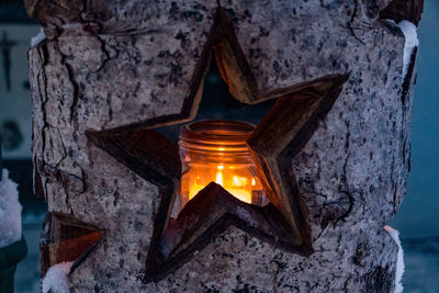 Close-up of illuminated candles on wooden log