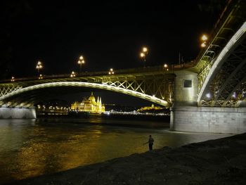 Illuminated bridge over river against sky at night