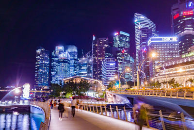 Illuminated bridge and buildings against sky at night