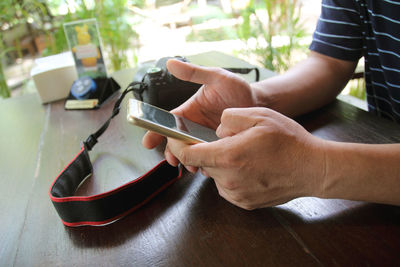 Midsection of man using mobile phone at table