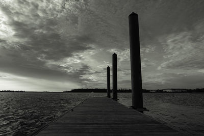 Wooden posts in sea against sky