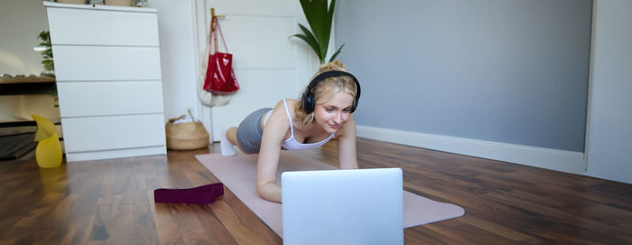 Full length of young woman sitting on chair at home