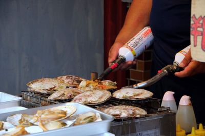 Close-up of man preparing food on barbecue grill