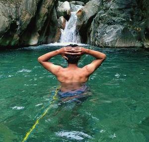 Rear view of shirtless man in water