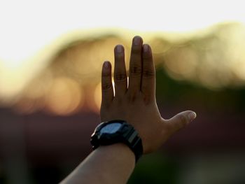 Cropped hand on man stop gesture during sunset