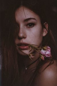 Portrait of beautiful woman with pink flower in mouth