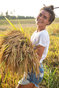 Side view of young woman standing by plants