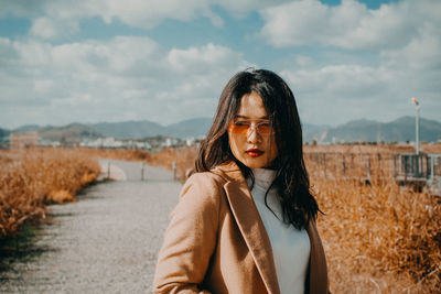 Portrait of young woman standing against sky