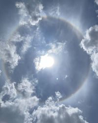 Low angle view of sunlight streaming through clouds