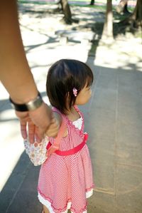 Cropped image of mother holding daughter hand while standing at sidewalk