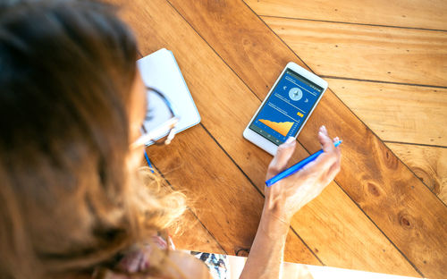 High angle view of woman using laptop on hardwood floor