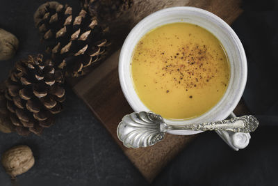 Butternut squash soup bowl with vintage spoon and pine cones, walnuts