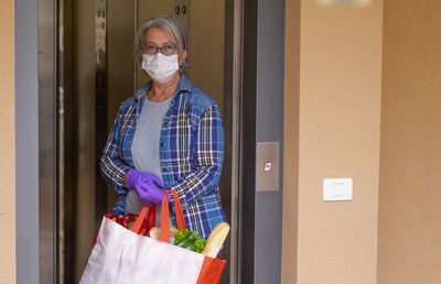 Portrait of senior woman standing on doorway