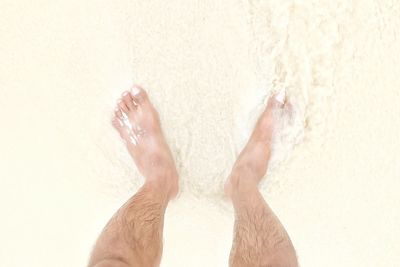 Low section of man on sand at beach