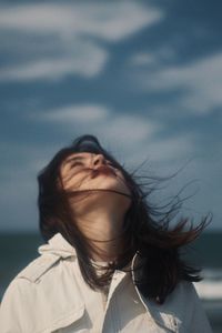 Portrait of young woman against sky