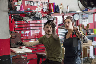 Mechanics pointing while working in auto repair shop